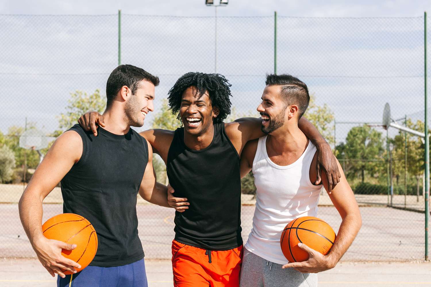 Vrienden die plezier hebben tijdens een rust na een straatbasketbalwedstrijd