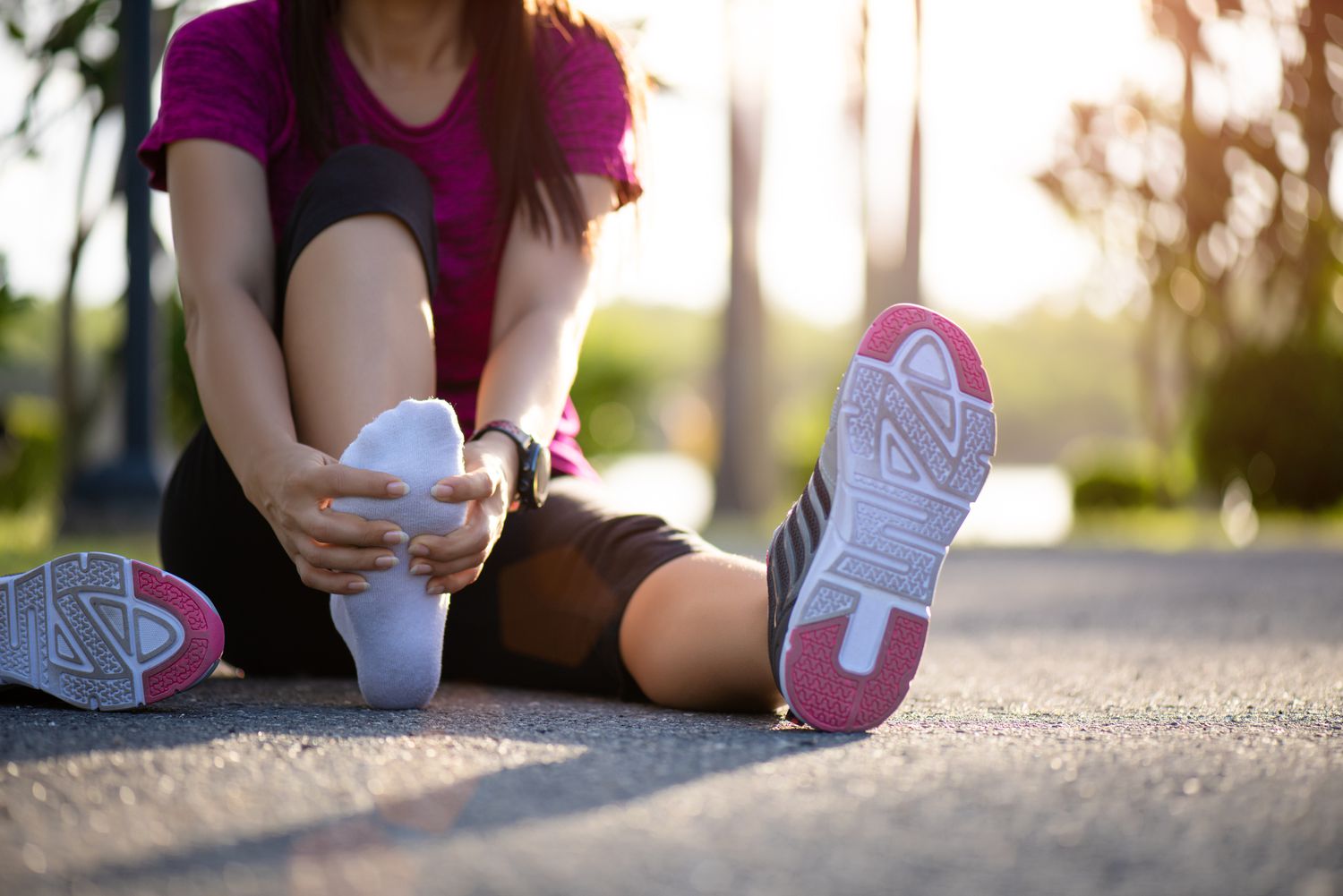 Jonge vrouw die haar pijnlijke voet masseert tijdens het sporten. Running Sport en oefening blessure concept.