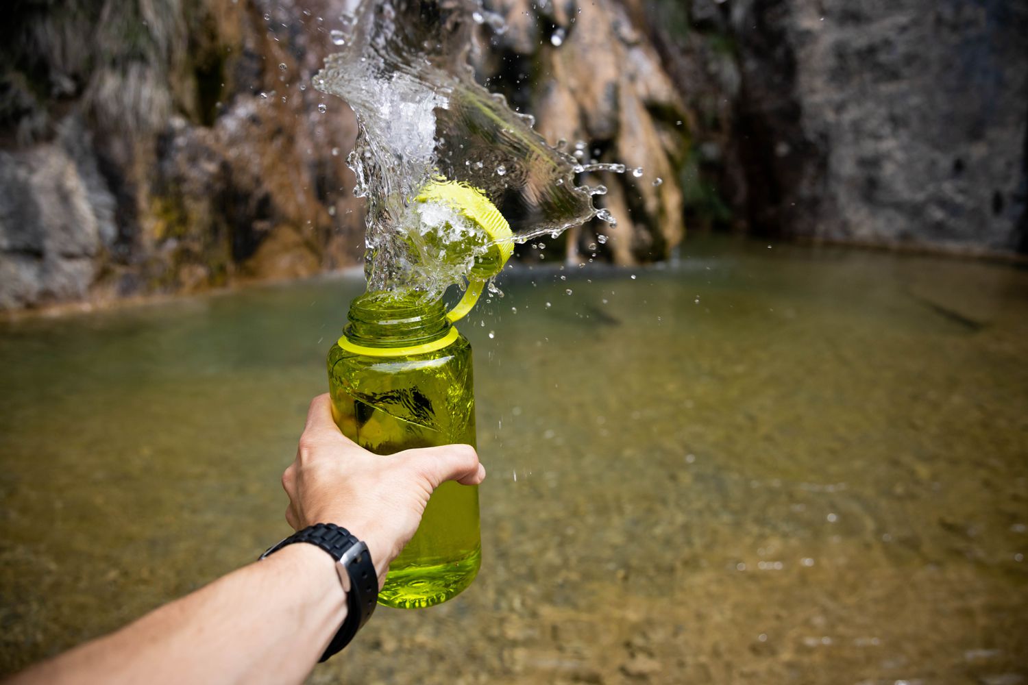 Spelen met waterspatten vullende fles water uit de rivier.