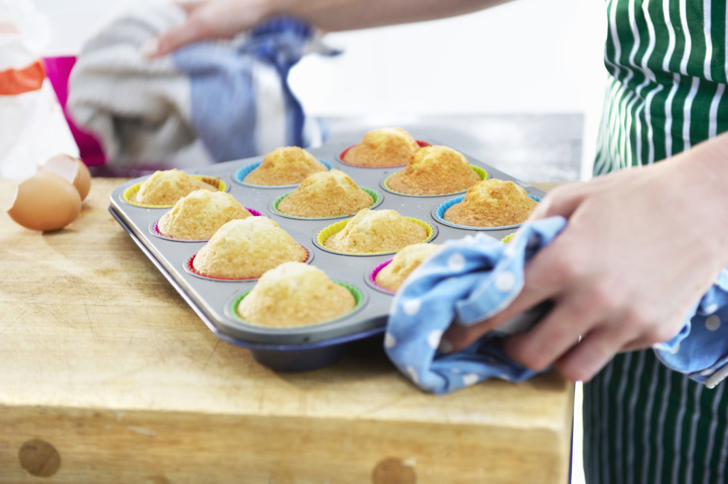 vrouw t zet muffins in blik op houten aanrecht