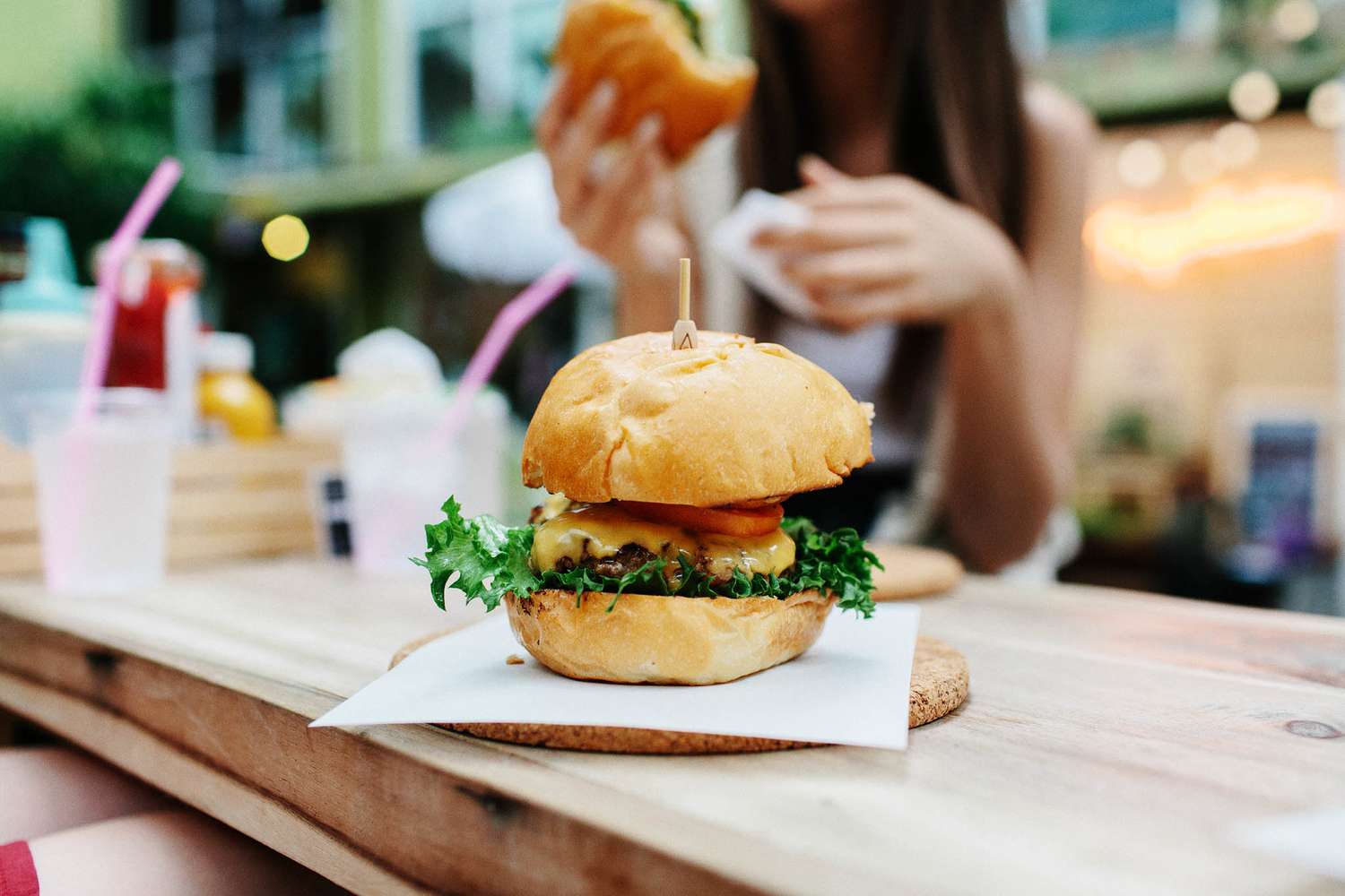 Close-up van hamburger met vrouw die op de achtergrond in het restaurant zit