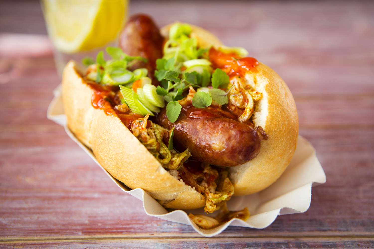 Aziatische hotdog, gebakken worst, pittige Chinese kool, hete chilisaus, lente-uitjes, tuinkers, broodje