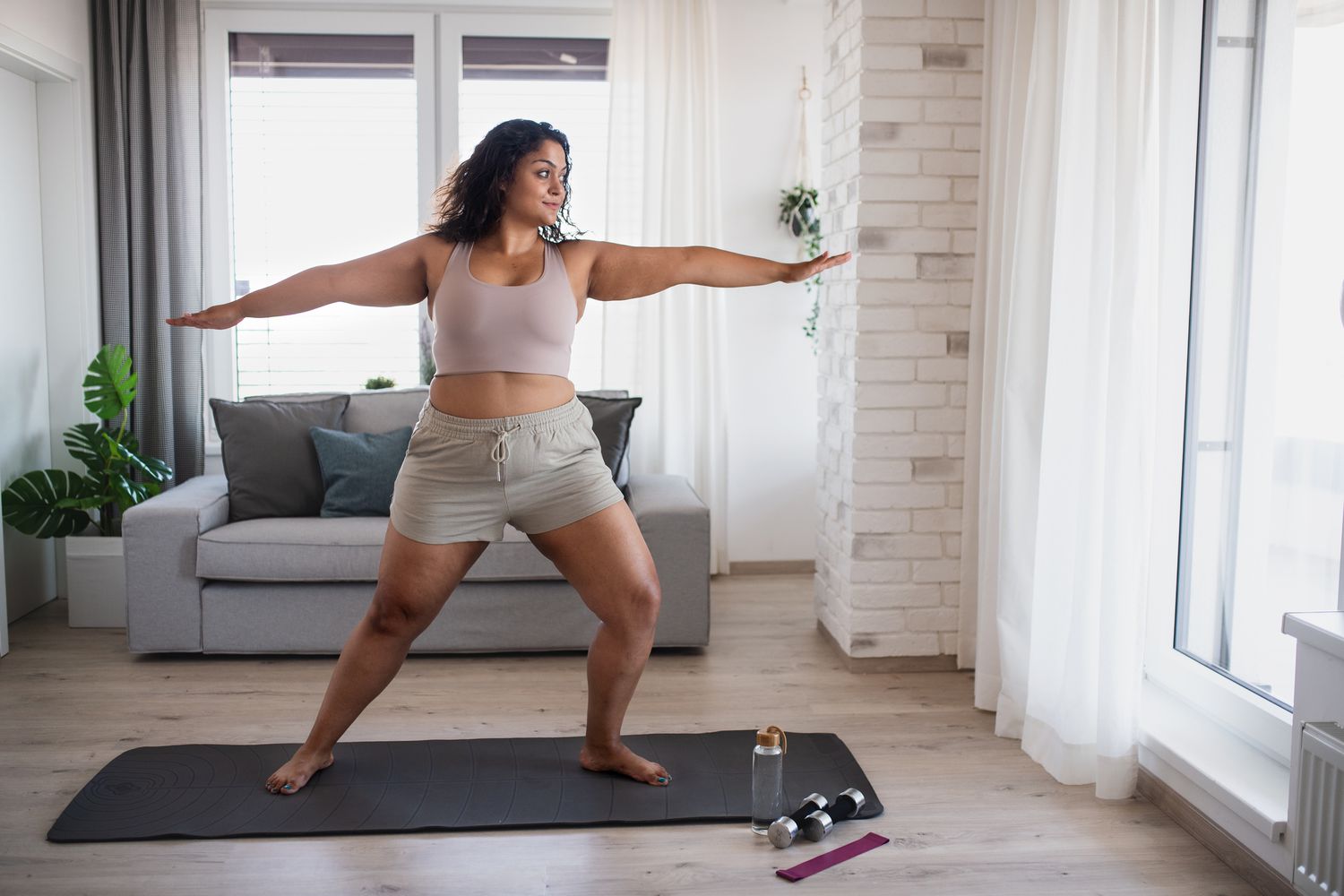 vrouw die yoga uitvoert in de woonkamer