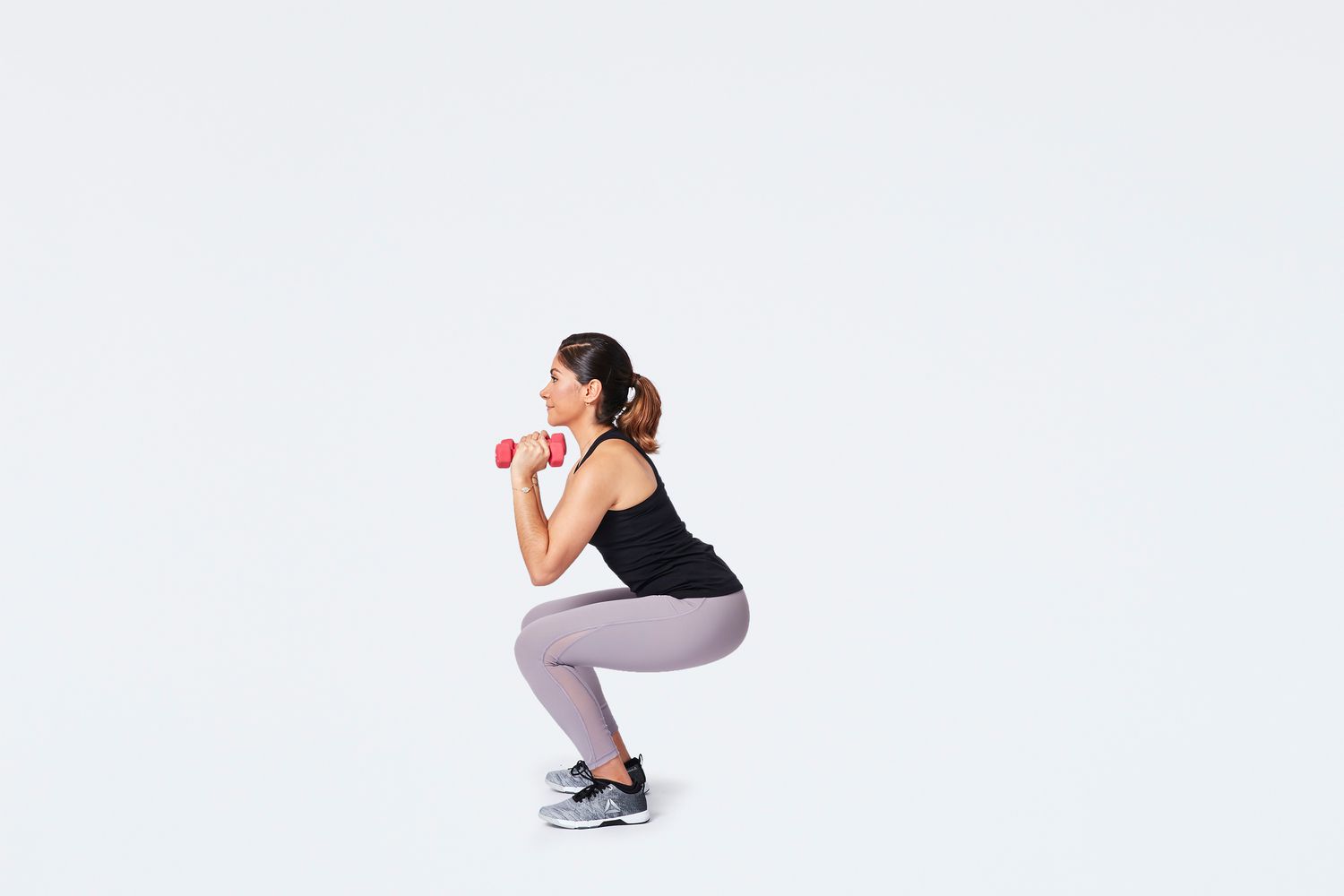 Vrouw die een dumbbell schouder squat uitvoert